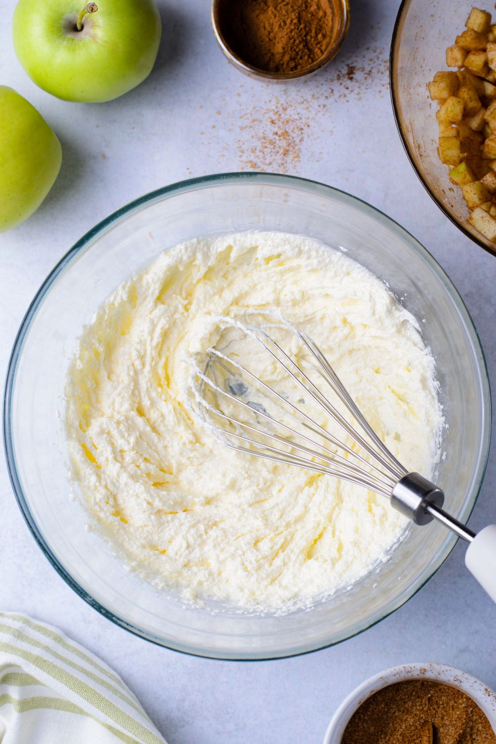 glass bowl with a whisk in it with wet ingredients for the Amish Apple Fritter Bread batter 
