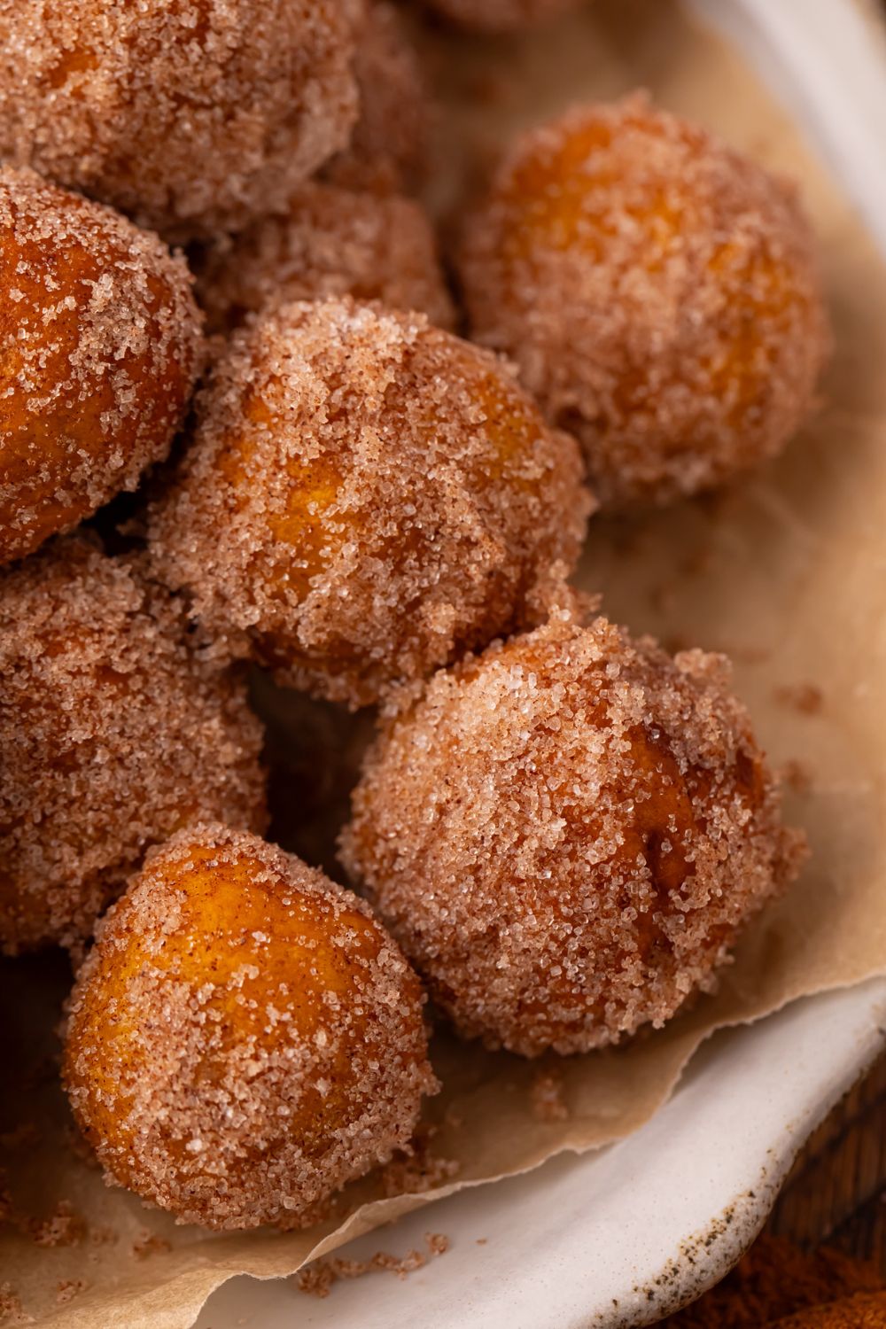 close up of a white plate full of a stack of Pumpkin Pie Donut Holes. You get a close up look of the cinnamon and sugar coating 