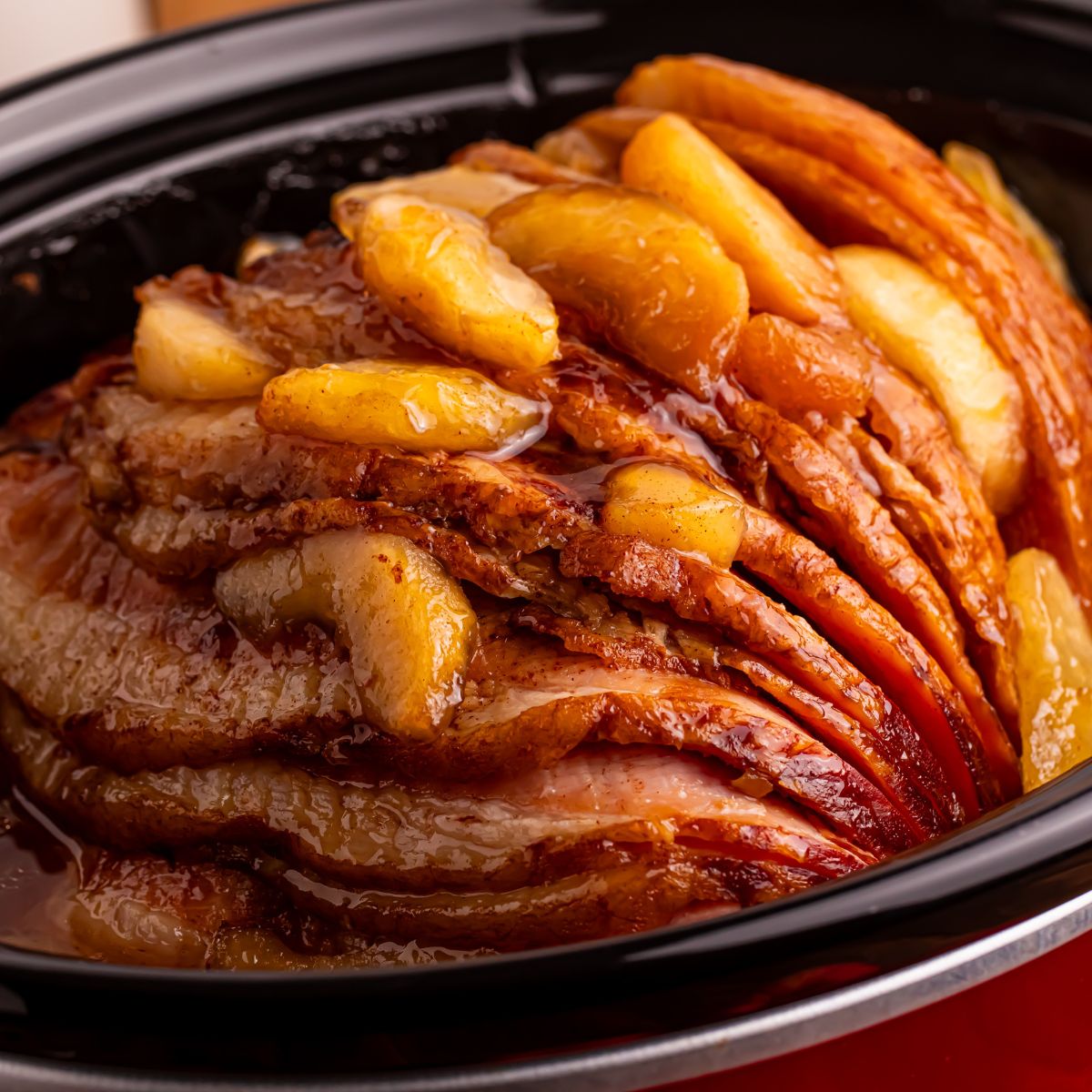 Slow Cooker Apple Glazed Ham in a red crockpot sitting on table 