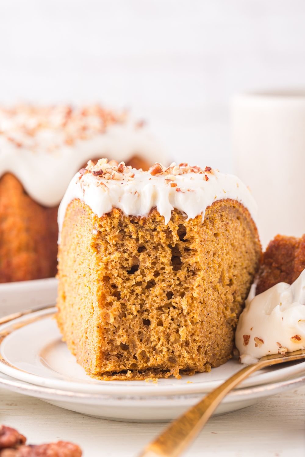 white plate with a slice of Pumpkin Bundt Cake on it with a bite taken out of it 