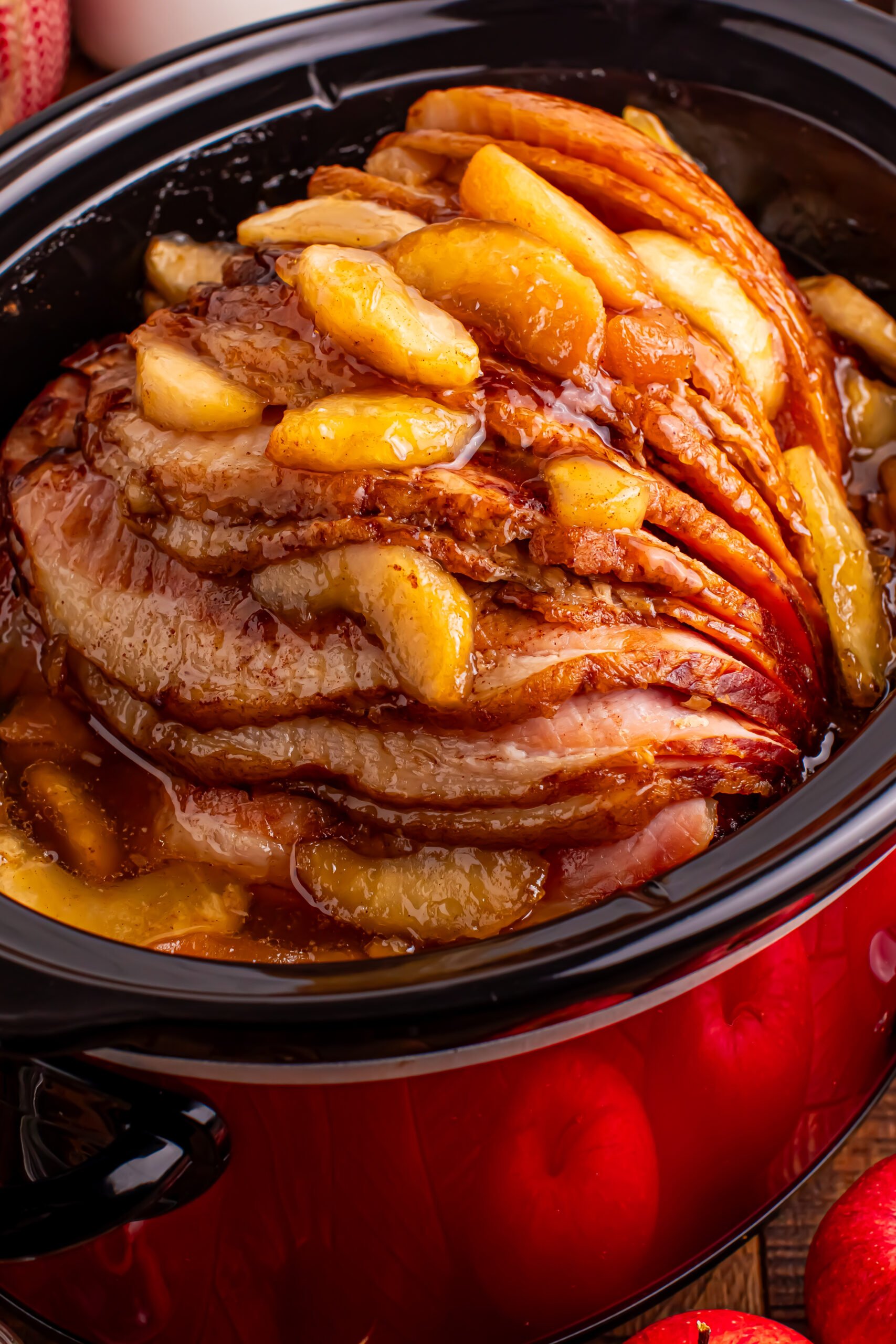 Slow Cooker Apple Glazed Ham in a black crock pot on a dark wood table 