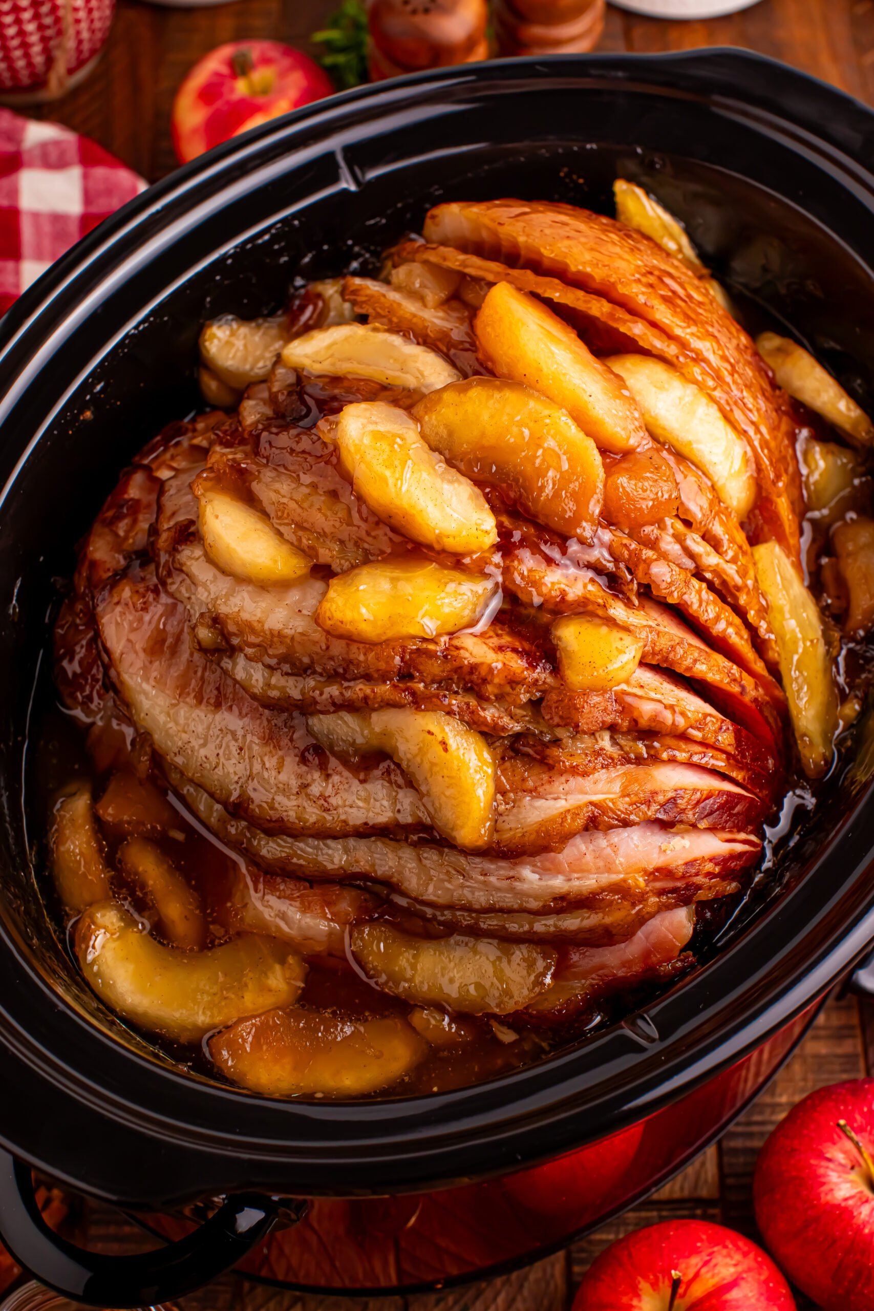 Slow Cooker Apple Glazed Ham in a black crock pot on a dark wood table 