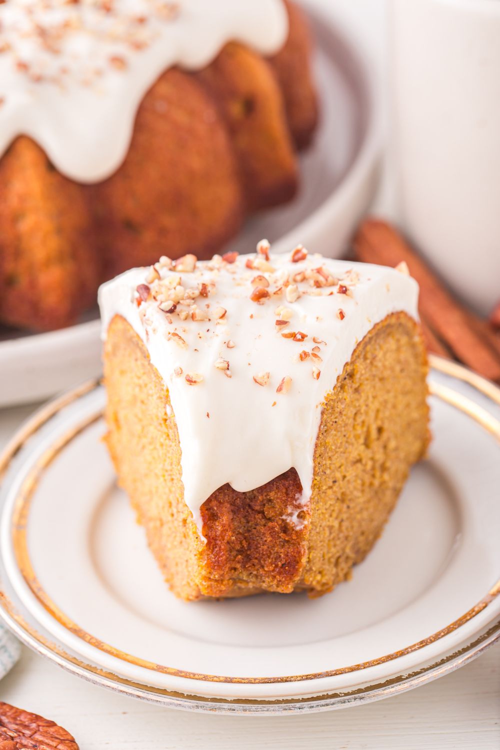 a whole Pumpkin Bundt Cake on a platter on table with a slice of cake in front 