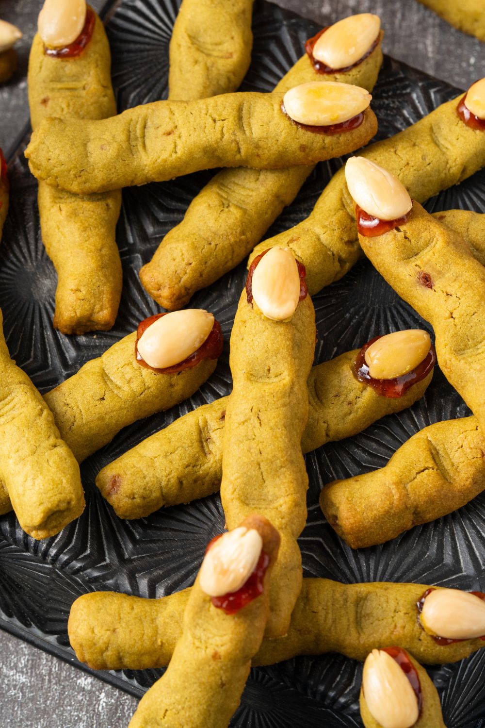 Witch Finger Cookies scattered all around the table and placed on a black tray 