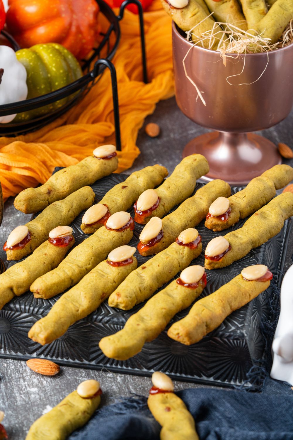 witches finger on a cooling rack on table with fall themed items behind it on table 