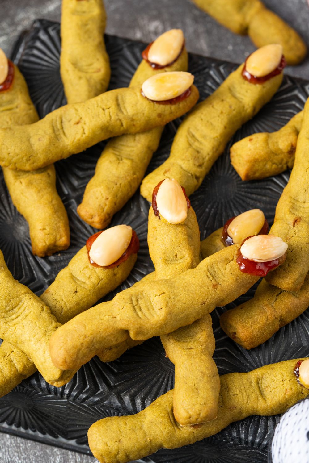 Witch Finger Cookies placed all around on a black square plate with cookies stacked on top of one another 
