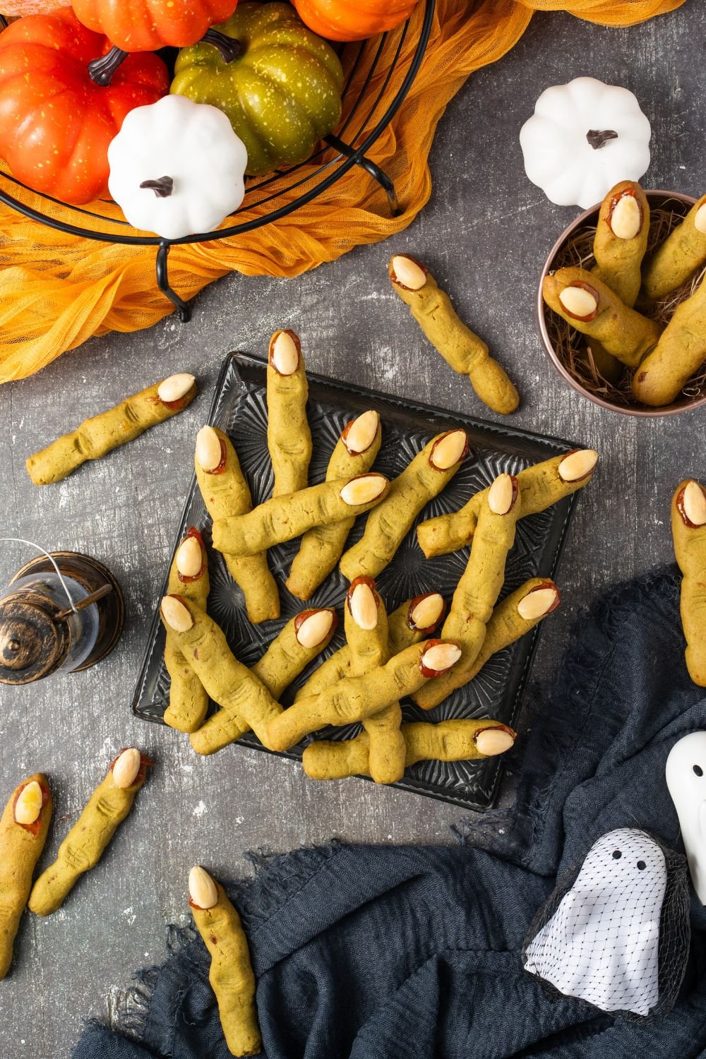 Witch Finger Cookies in a square plate on table with more scattered around the table with Halloween decor all around table 