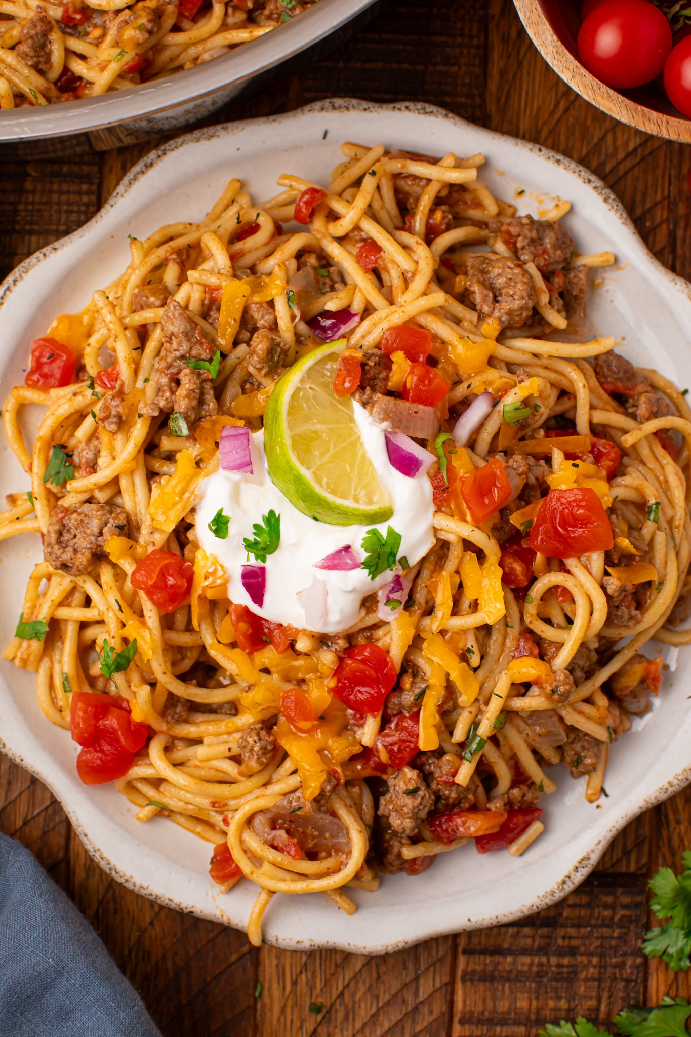 Plate of Cheesy Taco Spaghetti topped with sour cream and lime