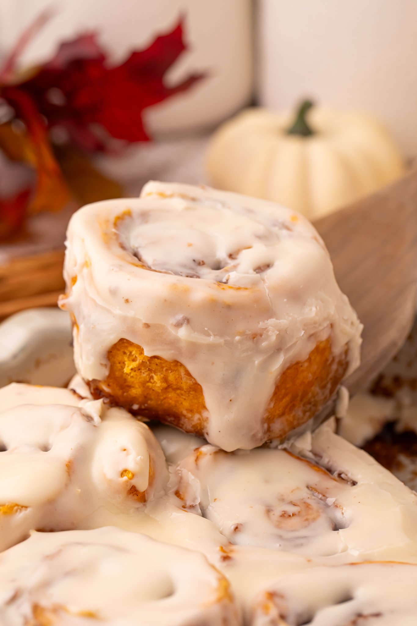 Easy 2 Ingredient Pumpkin Cinnamon Roll being lifted out of the baking dish