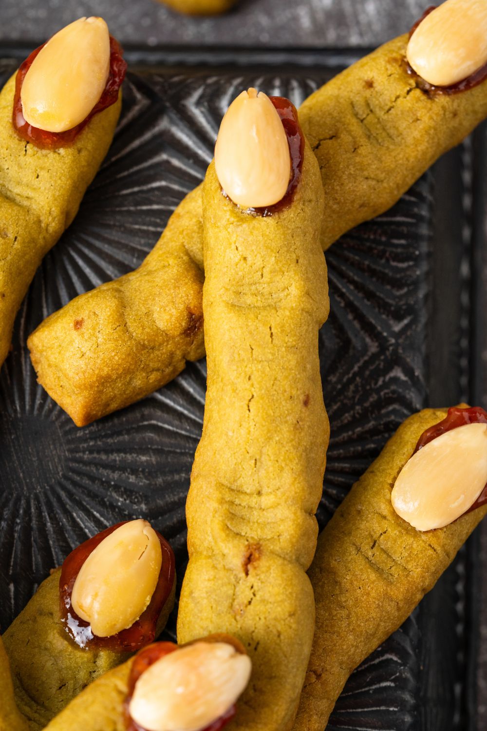 Witch Finger Cookies on a black tray with a close up of fingers 