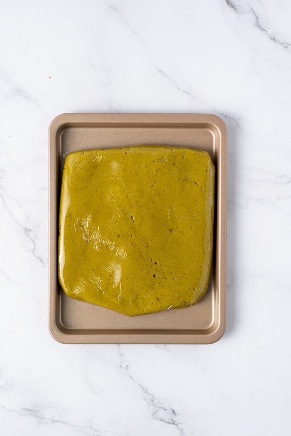 pistachio cookie dough shaped in a square on a baking sheet on table 