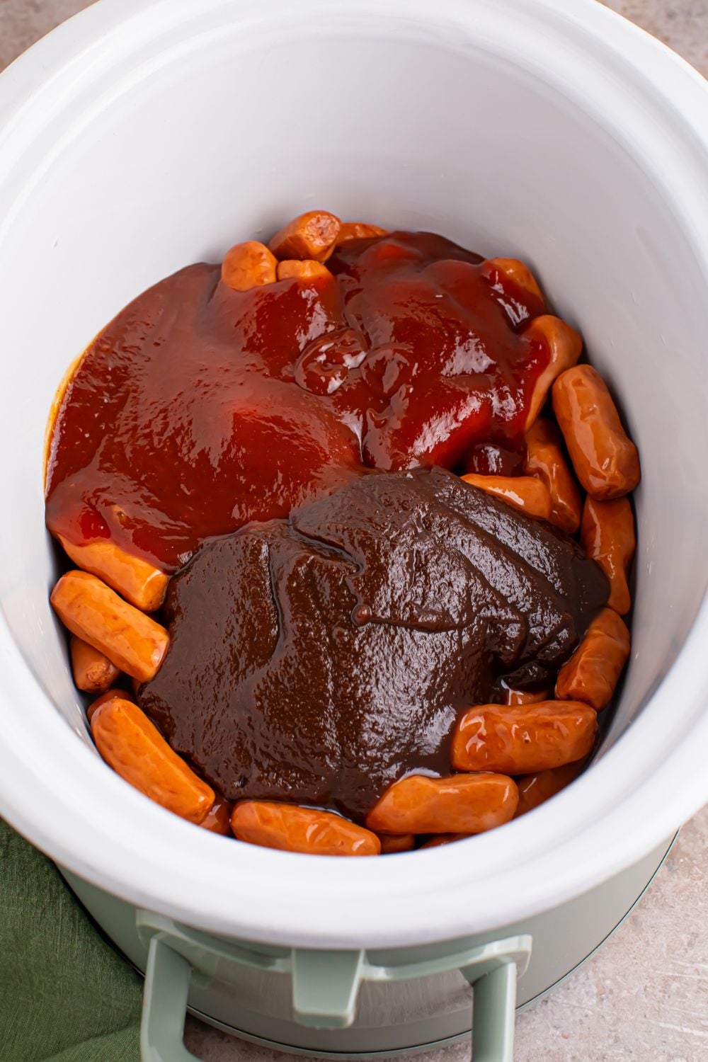 lil smokies with sauces on top in a white crockpot on the table