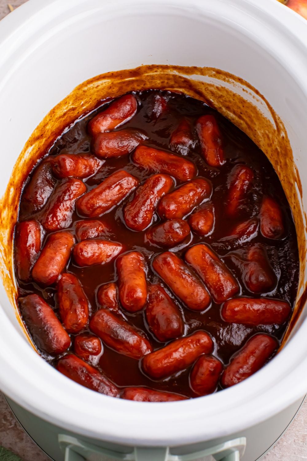 white crockpot full of bbq and apple butter coated little smokies 