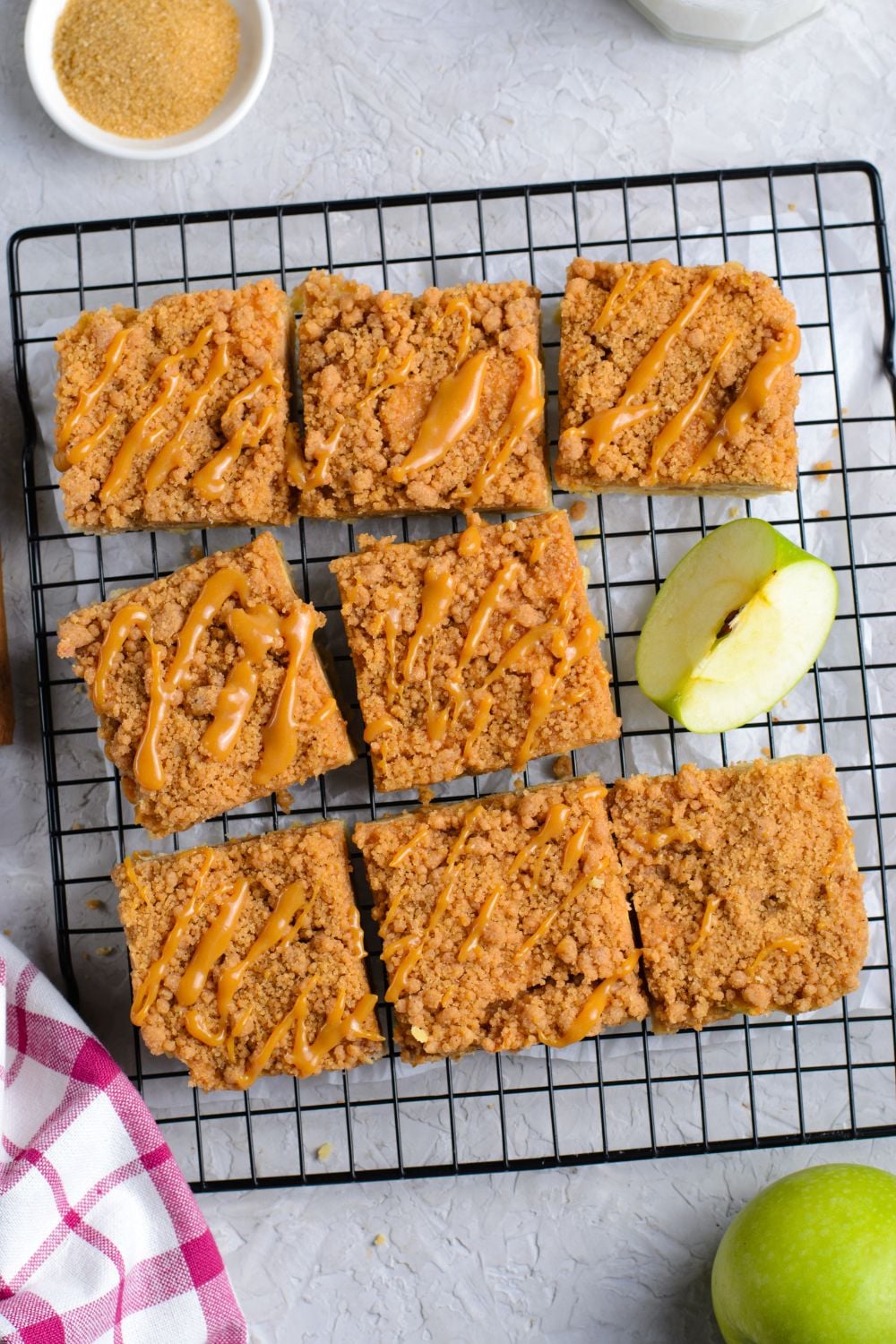 Caramel Apple Pie Bars on a cooling rack cut into squares with an apple slice to side 