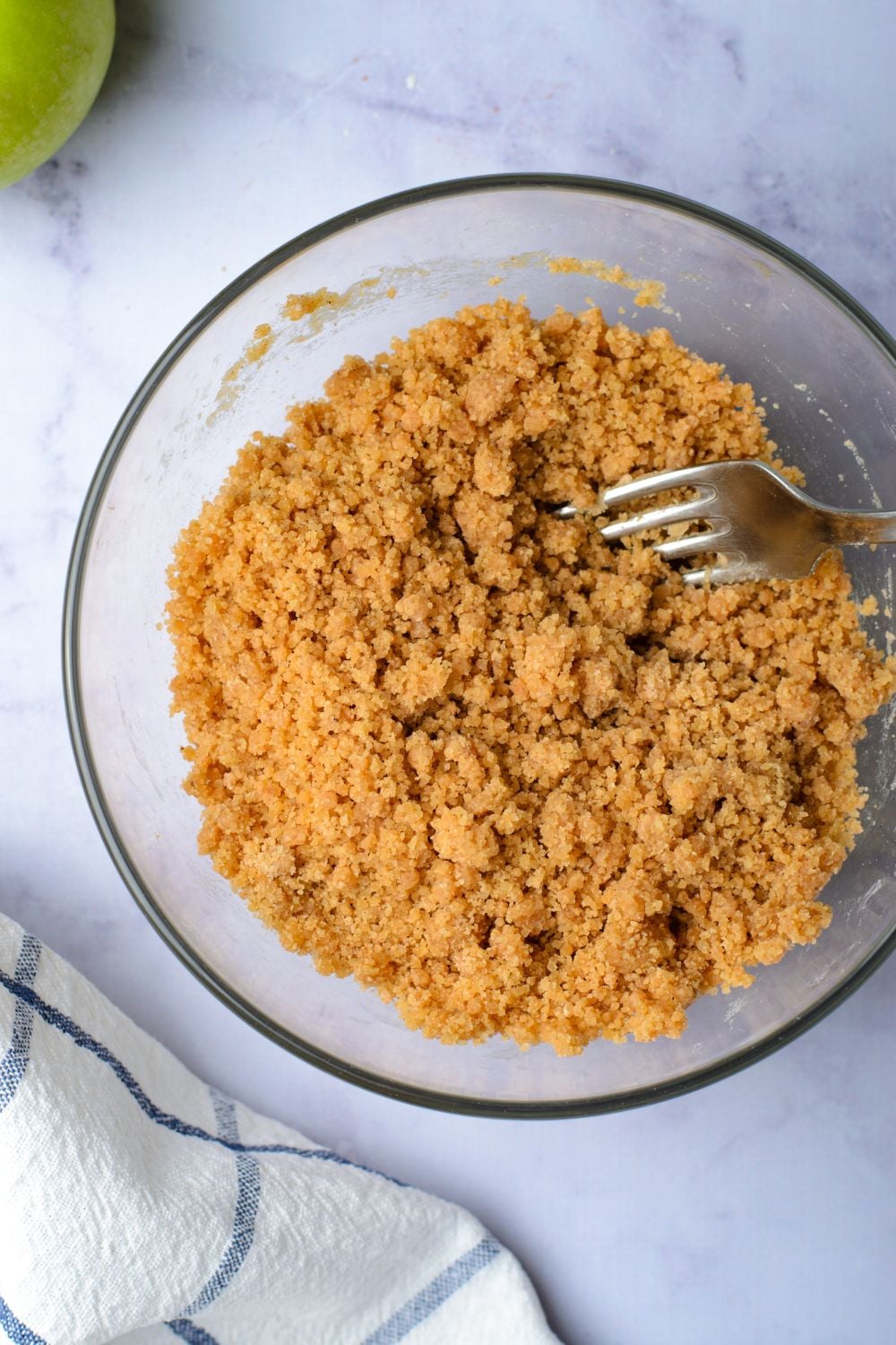 brown sugar crumble in a glass bowl with a fork to side 