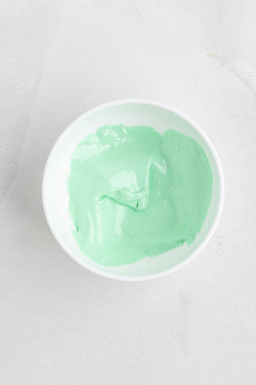 green colored meringue in a white bowl on the table 