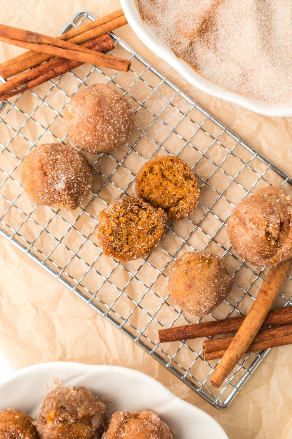 Pumpkin Spice Donut Holes on a cooling rack with cinnamon sticks around the edges of the rack