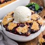 Blueberry Dump Cake in a bowl topped with a scoop of vanilla ice cream