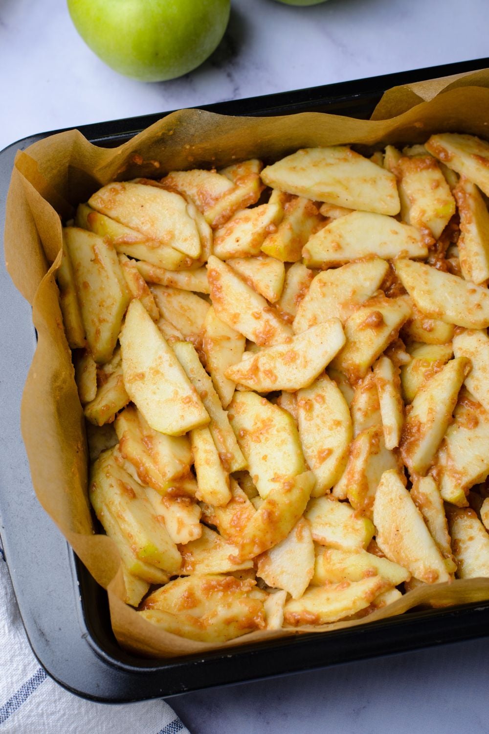 sliced apples that are seasoned in a pan on table 