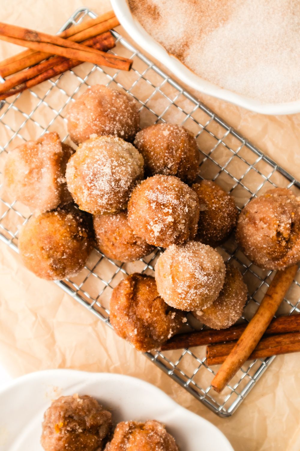 Pumpkin Spice Donut Holes on a metal tray with a few cinnamon sticks to the side 