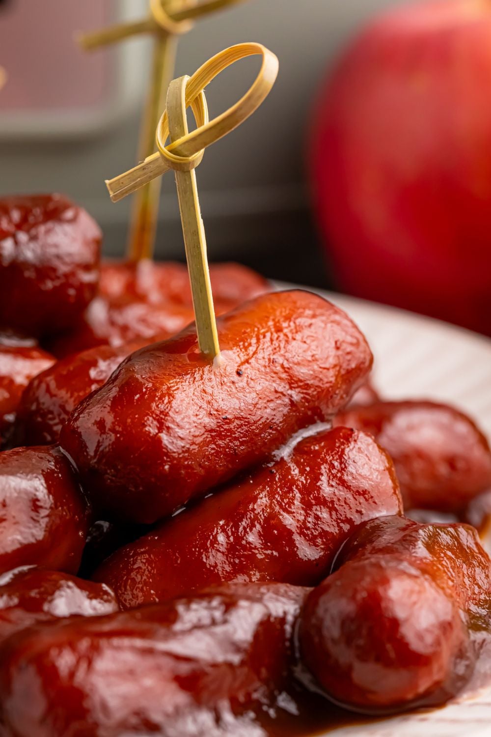 Apple Butter BBQ Little Smokies on a plate with toothpicks in a few and an apple and crockpot sitting in the background 