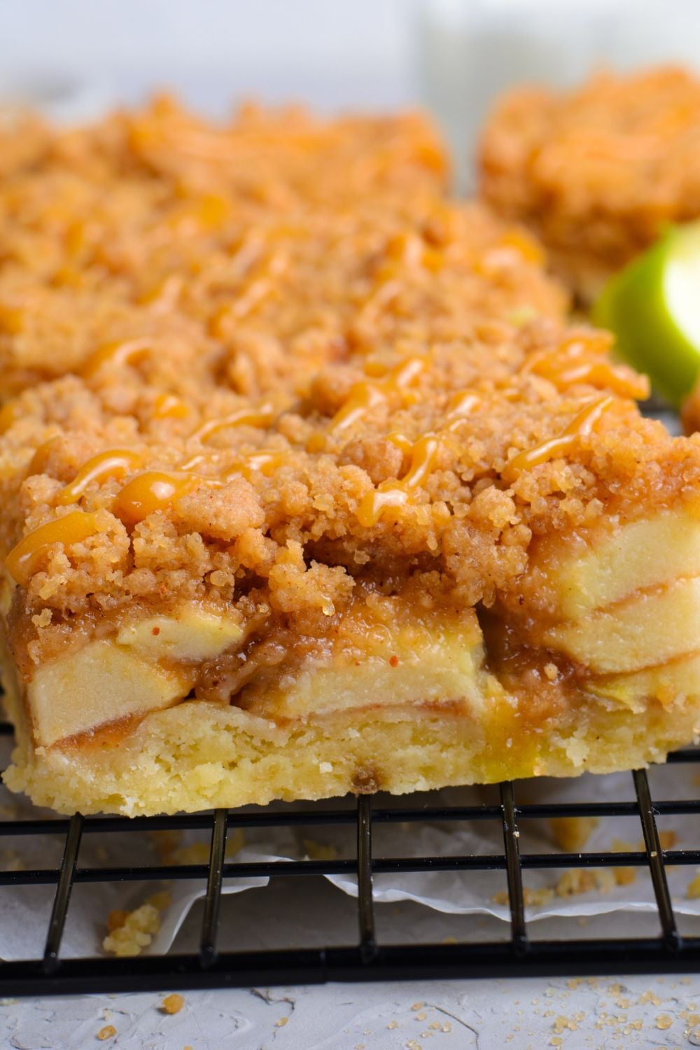 close up of a sliced Caramel Apple Pie Bar on a cooling rack with a green apple to the side 