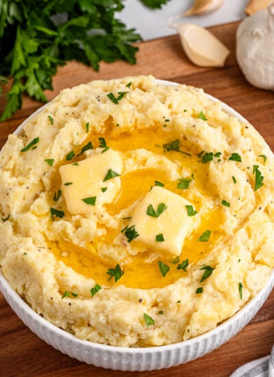 Garlic Mashed Potatoes in a white bowl sitting on a dark wood table
