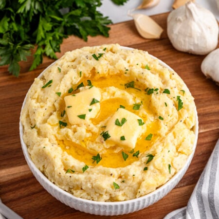 Garlic Mashed Potatoes in a white bowl sitting on a dark wood table