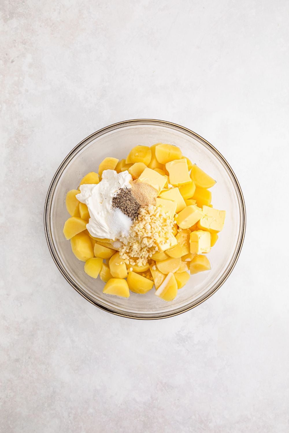cooked potatoes, sour cream, spices and more in a glass bowl on white table 