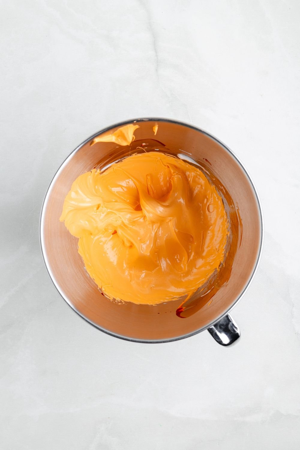 metal mixing bowl full of orange meringue 