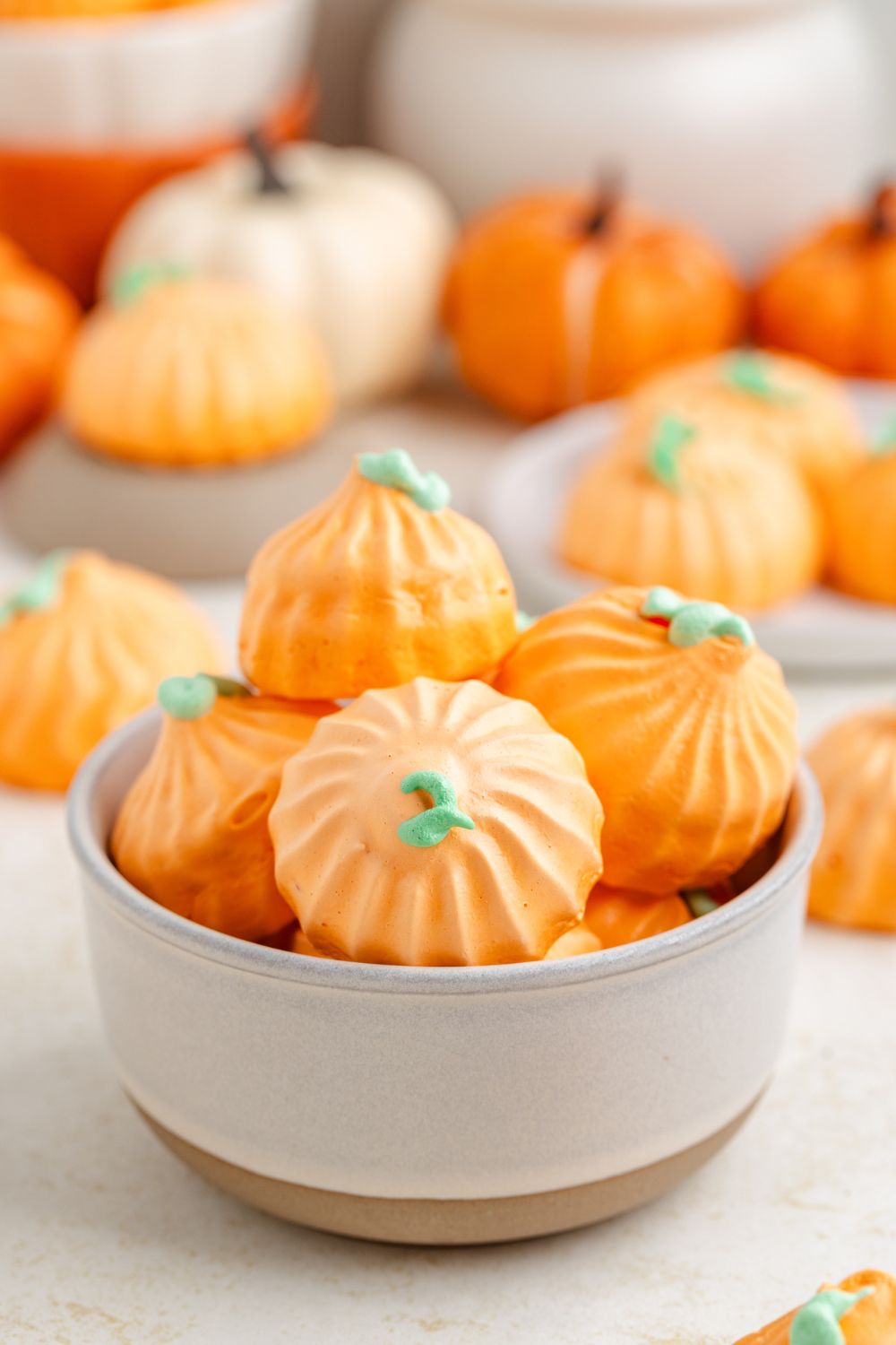 Pumpkin Meringues in a cream bowl on table with small pumpkins and cookies placed nicely around table for a fall look 