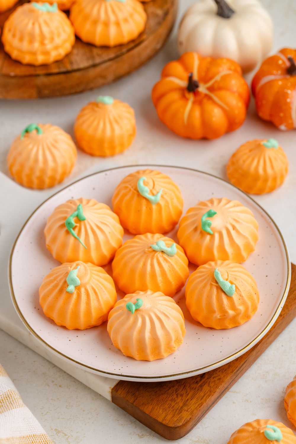 Pumpkin Meringues on a white plate on table with more cookies around and a few small pumpkins 