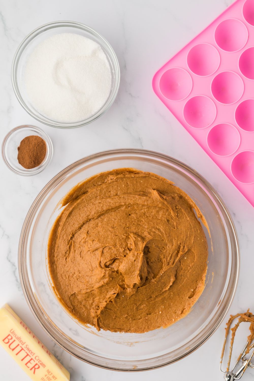 a glass bowl with Pumpkin Spice Donut Hole batter in it, with the donut pan to the side 