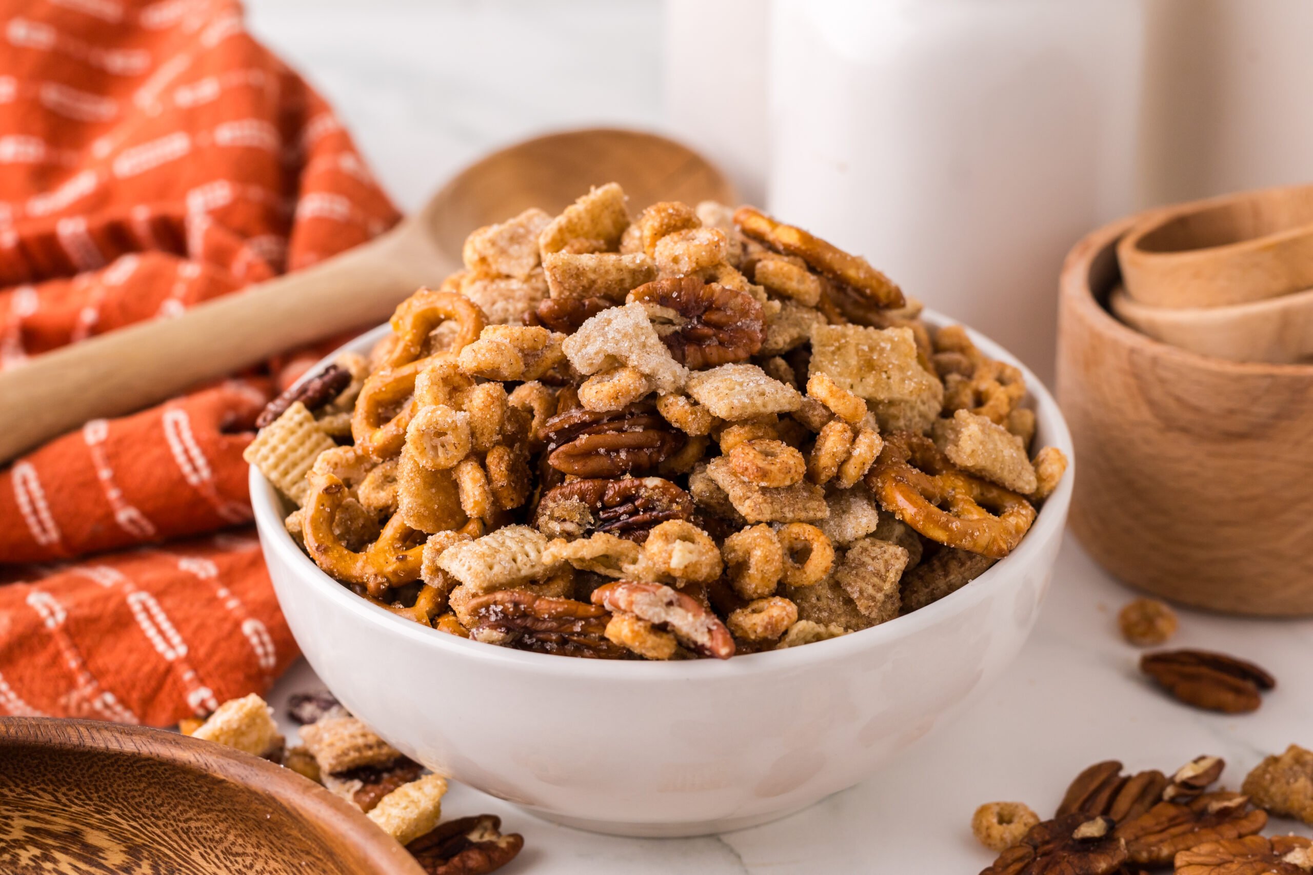 Pumpkin Spice Chex Mix in a white serving bowl on a white marble table 