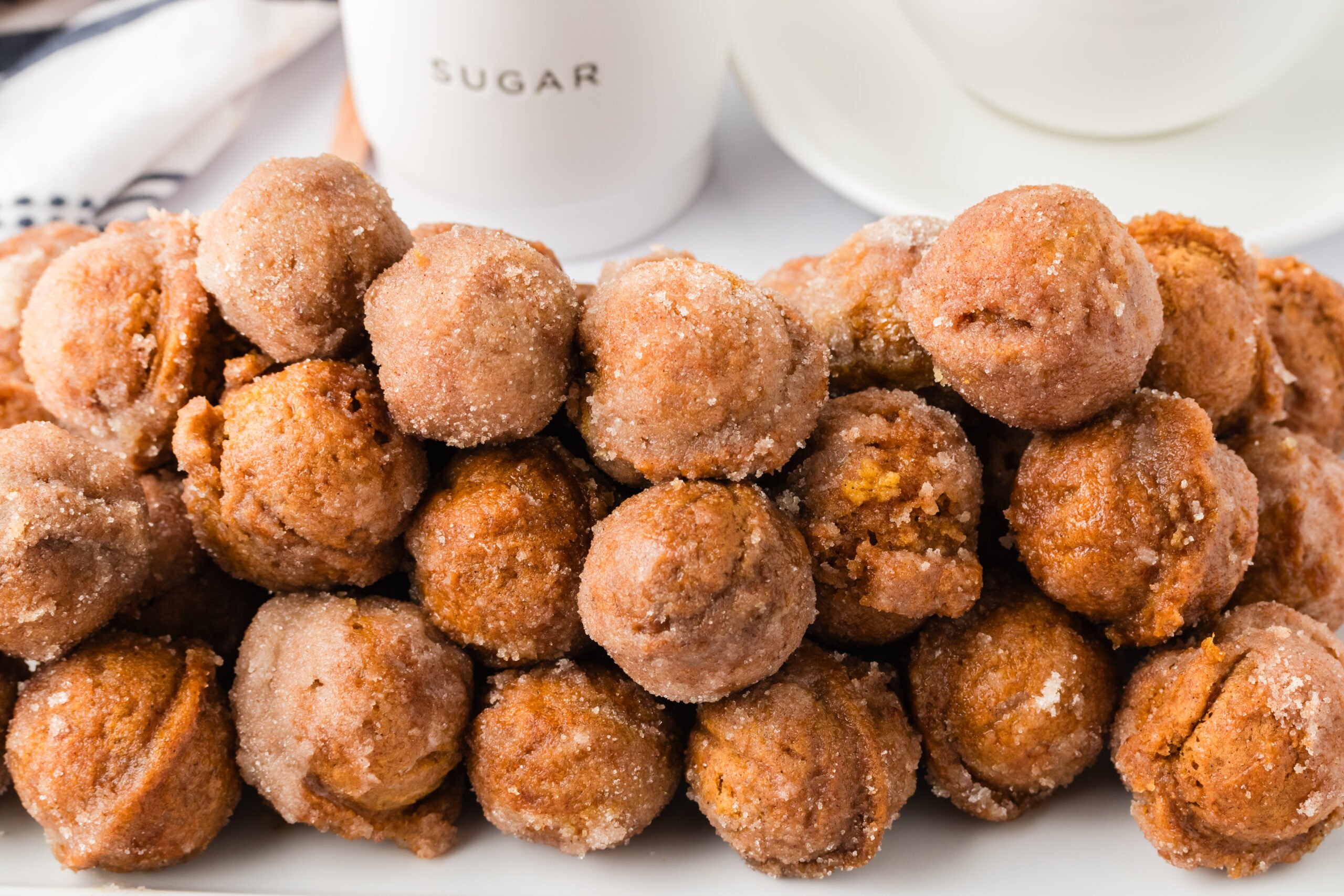 a huge bunch of the Pumpkin Spice Donut Holes on a white plate with a containe