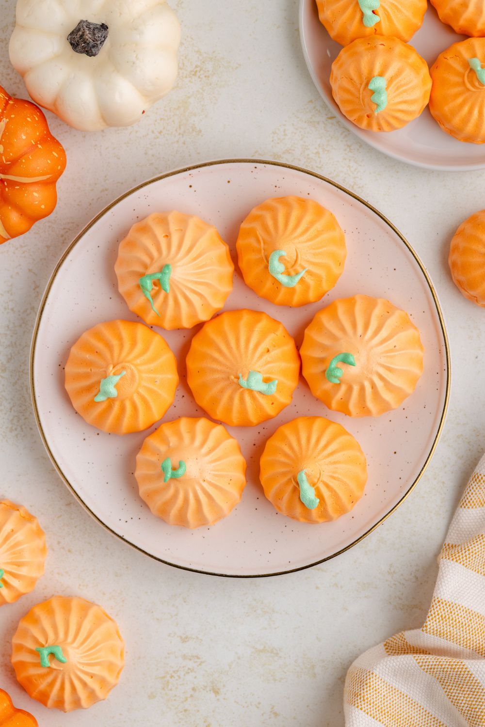 looking down at table with a plate in center with Pumpkin Meringues on it, and then more cookies in bunches around table and mini pumpkins 
