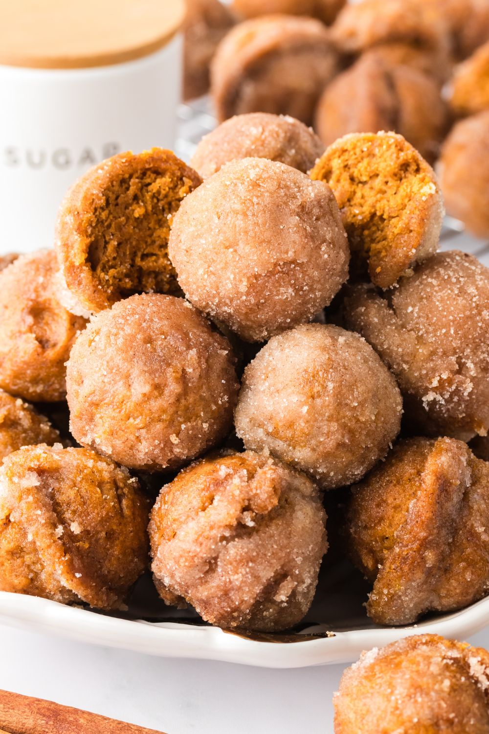 Pumpkin Spice Donut Holes stacked on a plate with a few cut in half to show the centers of the donuts 