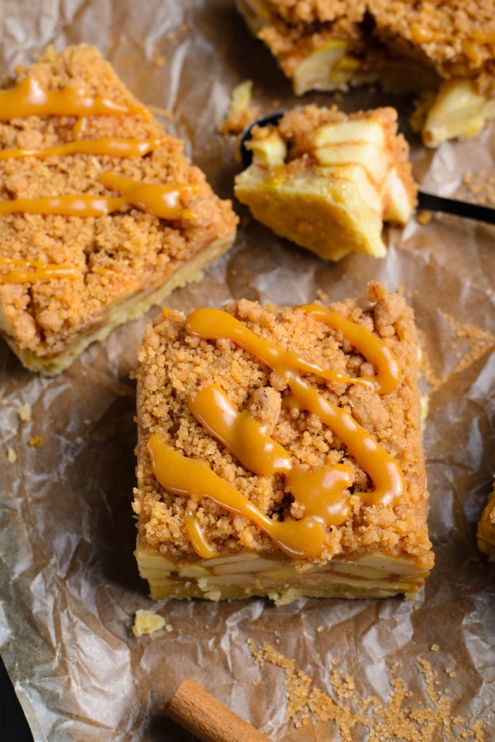 a few apple bars on table with parchment paper with caramel sauce drizzled on each bar