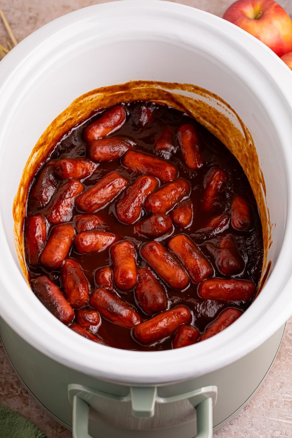 looking down on a white crockpot full of apple butter little smokies 