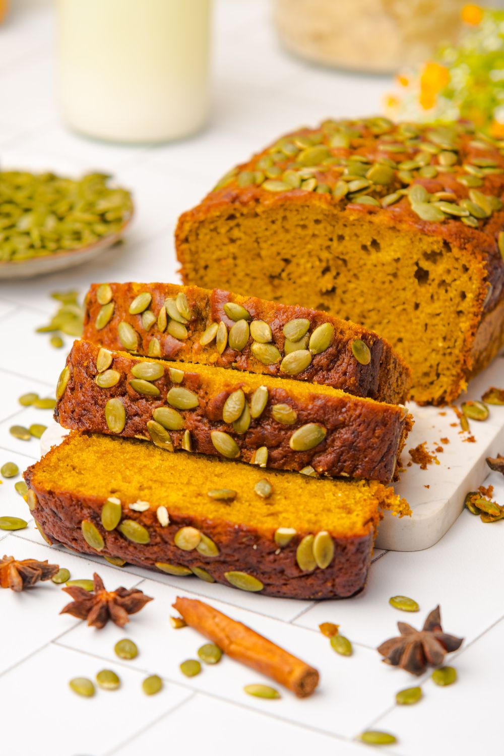 Starbucks Pumpkin Bread placed on table with cinnamon sticks, anise, and pumpkin seeds around the table 