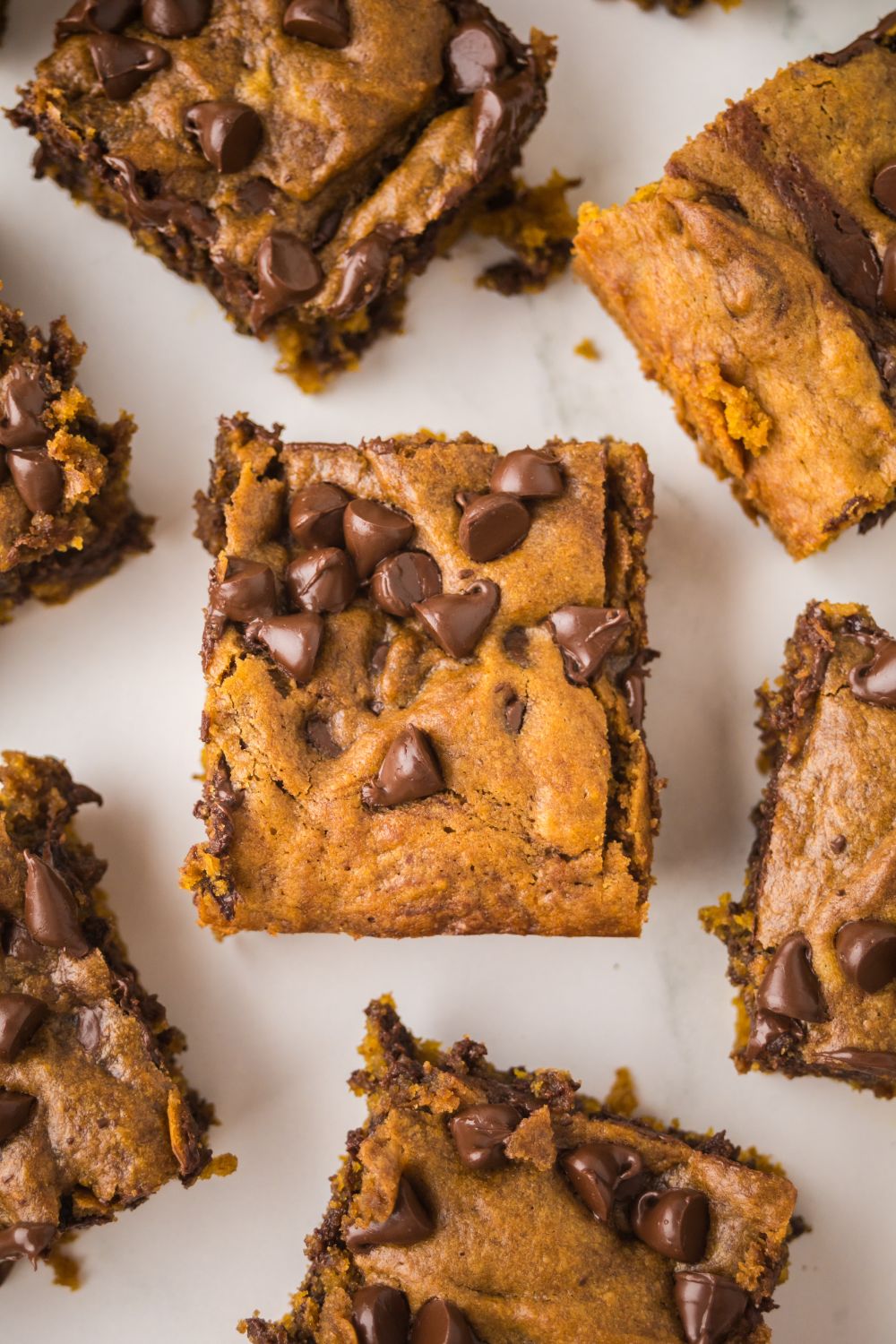 square slices of Brown Butter Pumpkin Chocolate Chip Bars placed around the table 