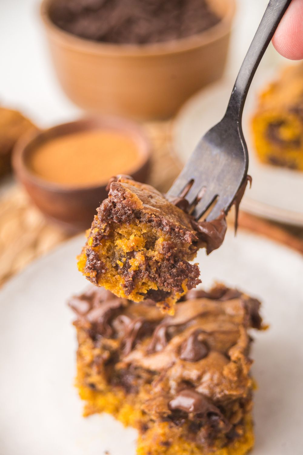 Brown Butter Pumpkin Chocolate Chip Bar on a white plate with a fork with a bite taken out of the bar on the fork 