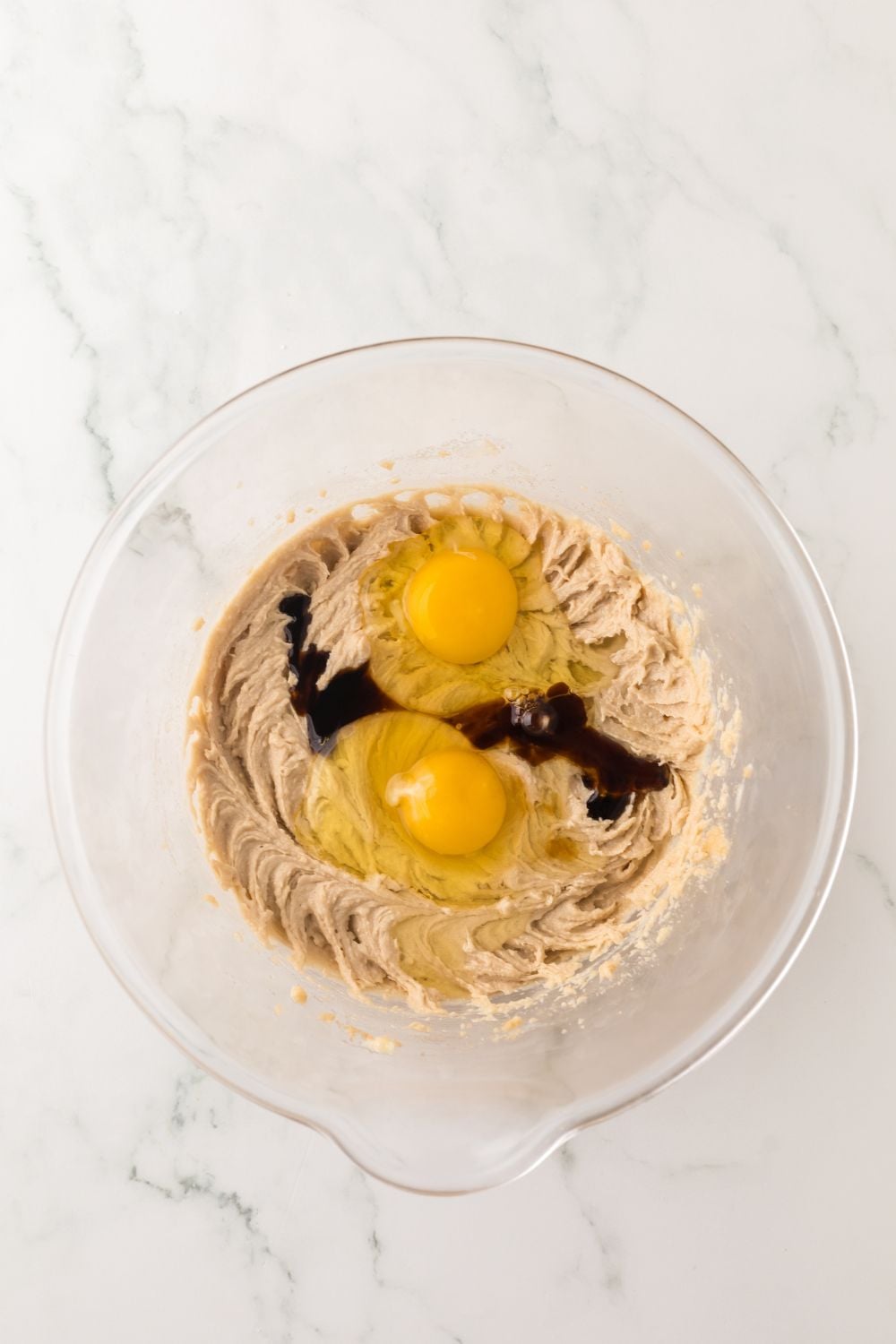 cheesecake cookie dough batter being mixed up with two eggs on top of cookie dough 