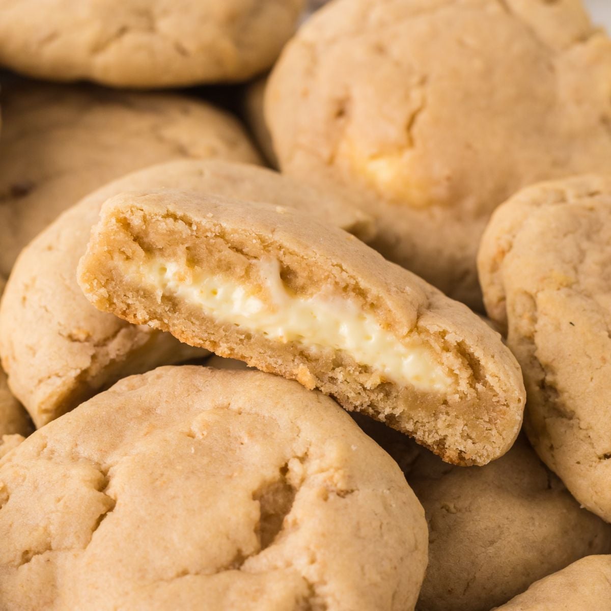 New York Cheesecake Stuffed Cookies spread on table with one cut in half 