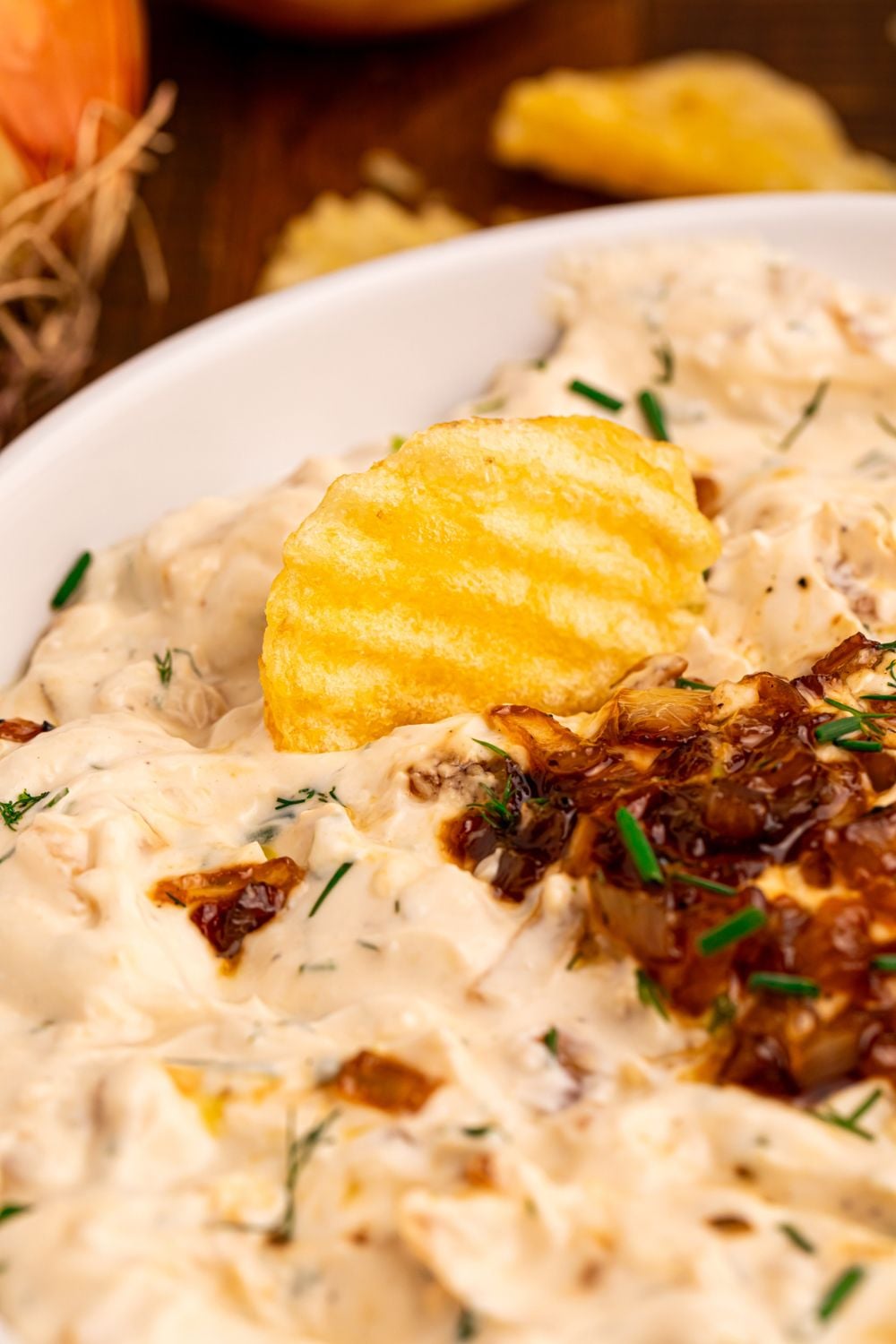 Caramelized Onion Chip Dip with a chip pressed into the dip 