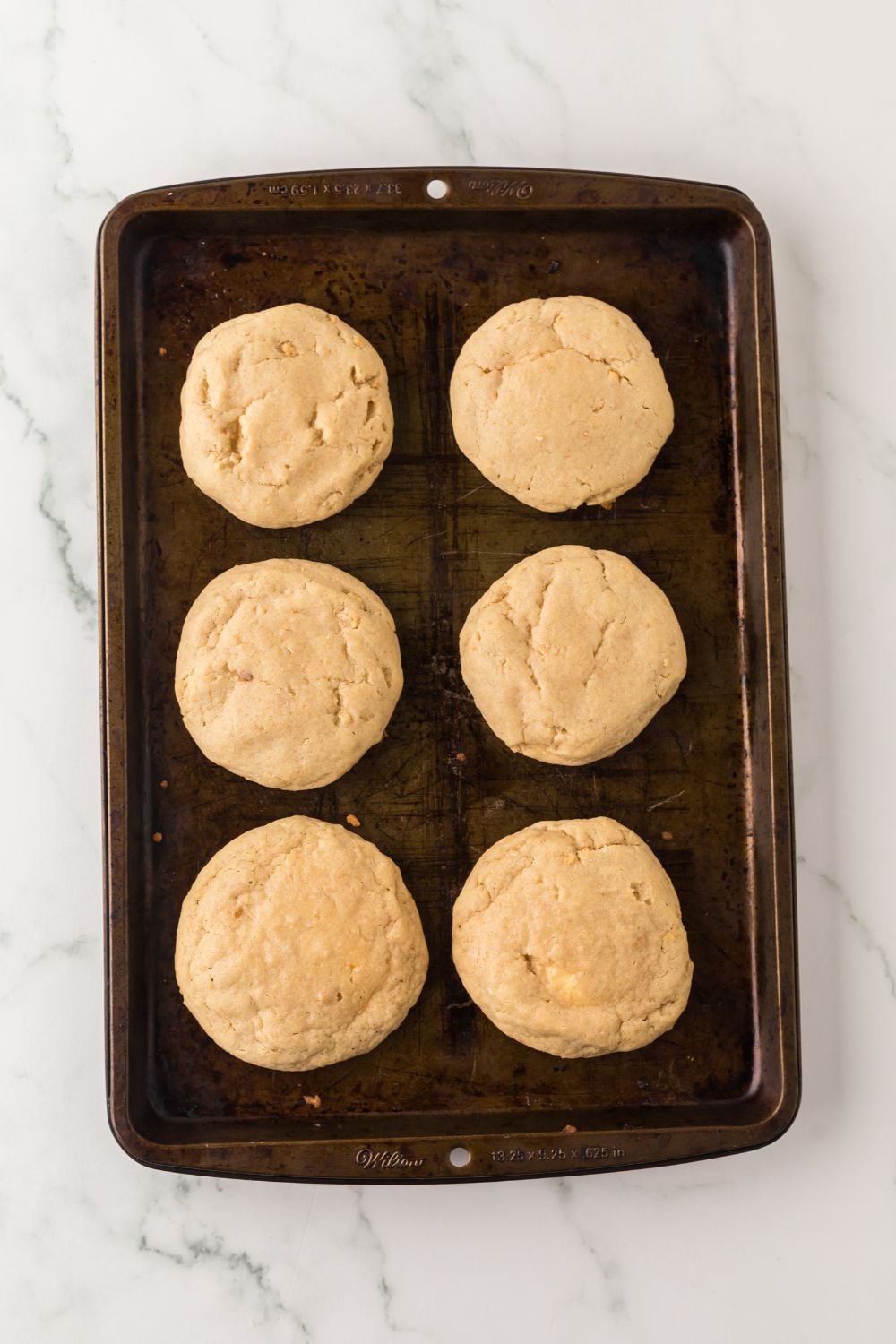 baked cheesecake stuffed cookies on marble counter on a baking sheet 