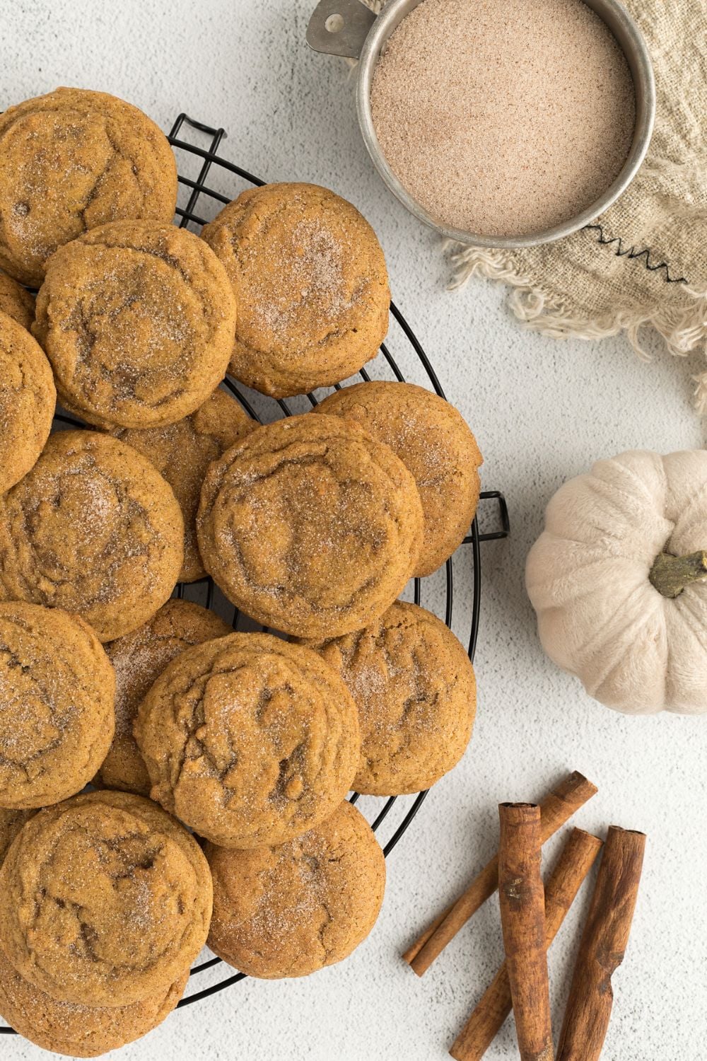 Pumpkin Snickerdoodle Cookies on a platter with sugar, pumpkin and cinnamon sticks to the side 