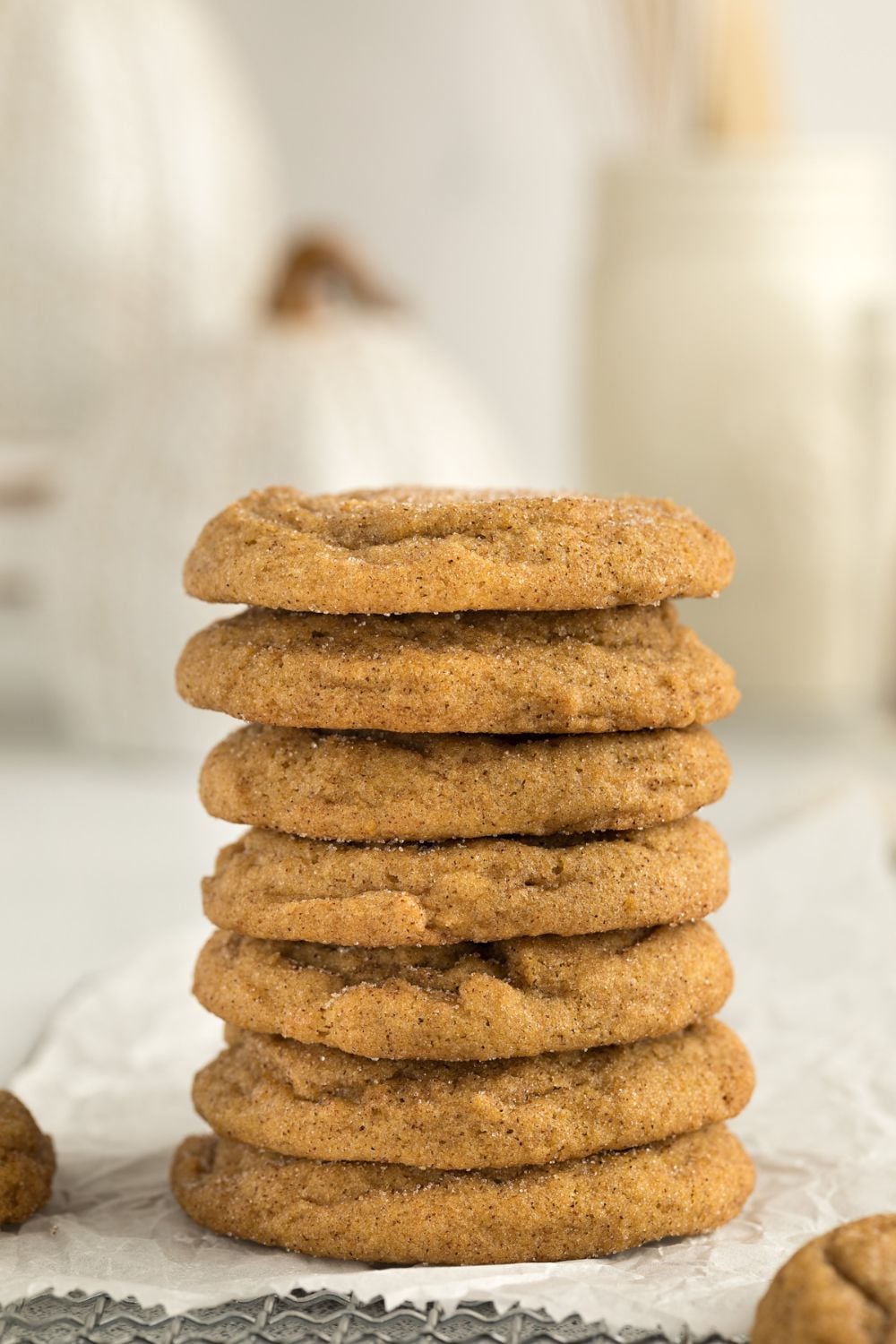 stack of pumpkin cookies on table with a glass of milk to side on table 