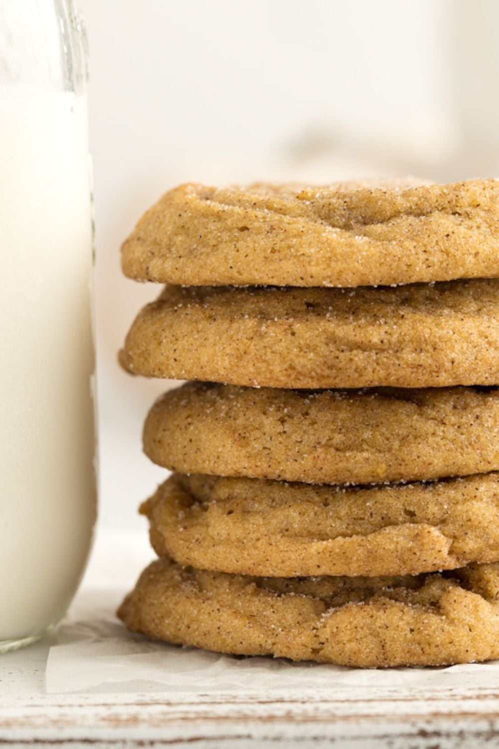 close up of a stack of pumpkin spice cookies with a glass of milk to side 