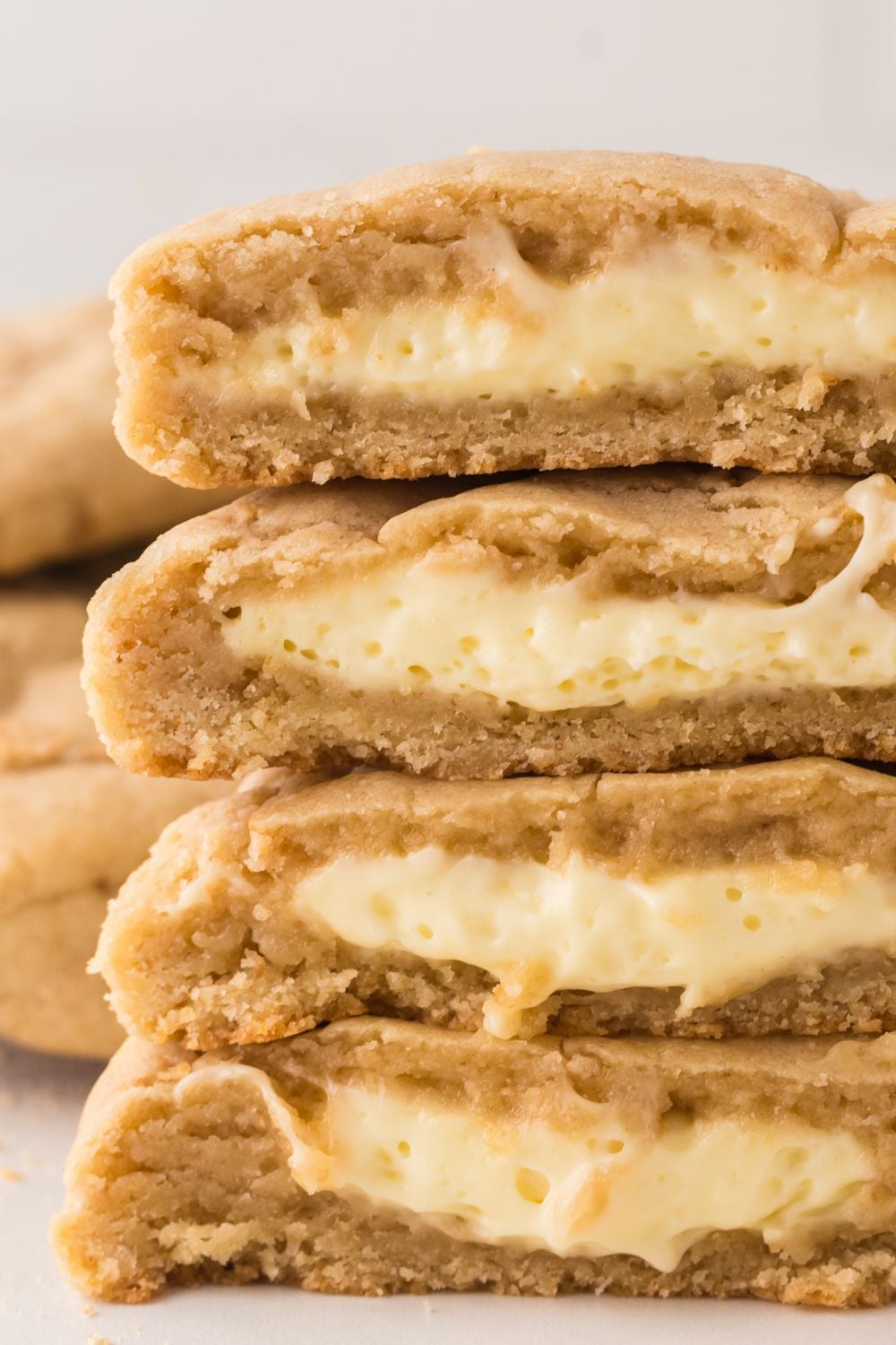 soft stuffed cheesecake cookies stacked on top of one another and cut in half to show the filling